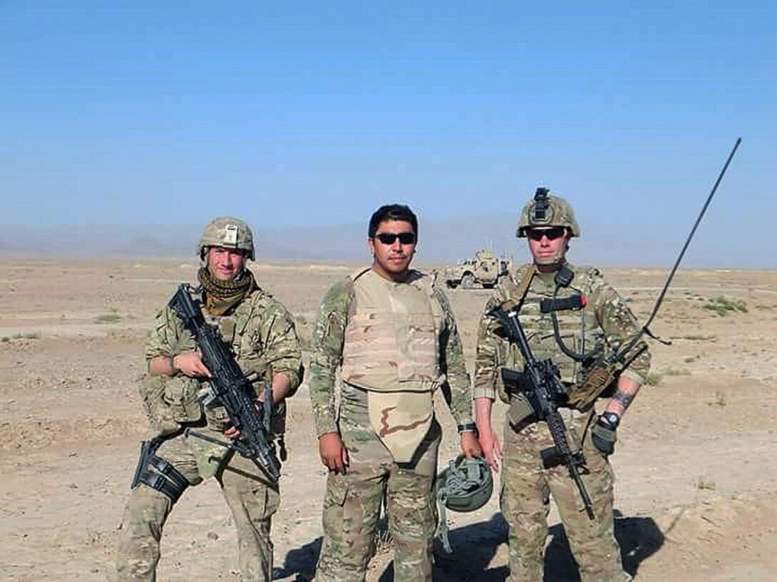 An Afghan interpreter stands with two soldiers in Afghanistan.