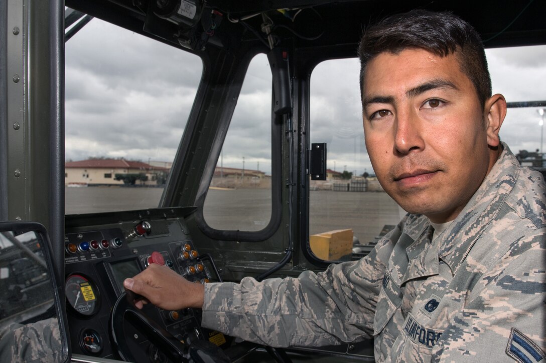 An airman poses for a photo while behind the wheel of a military vehicle.