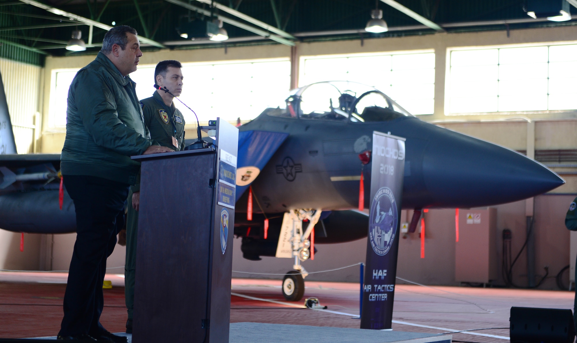 Greek Minister of Defence Panos Kammenos addresses distinguished guests and media in front of a 492nd Fighter Squadron F-15E Strike Eagle from Royal Air Force Lakenheath, England during an INIOHOS 18 event at Andravida Air Base, Greece, March 20, 2018. Thirteen F-15Es from the 492nd FS are participating alongside the Hellenic Air Force and other Allies and partner nations during the exercise. (U.S. Air Force photo/1st Lt. Elias Small)
