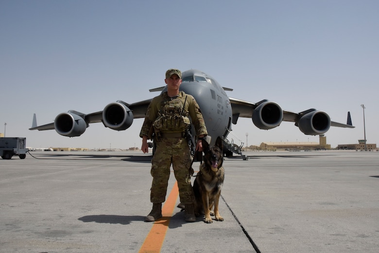 Staff Sgt. Steven Watkins and Military Working Dog, Onyx, pose for a photo in front of a KC-135 Stratotanker during a deployment. While deployed, the pair worked with an Explosive Ordnance Disposal uni and a Navy Seals unit.