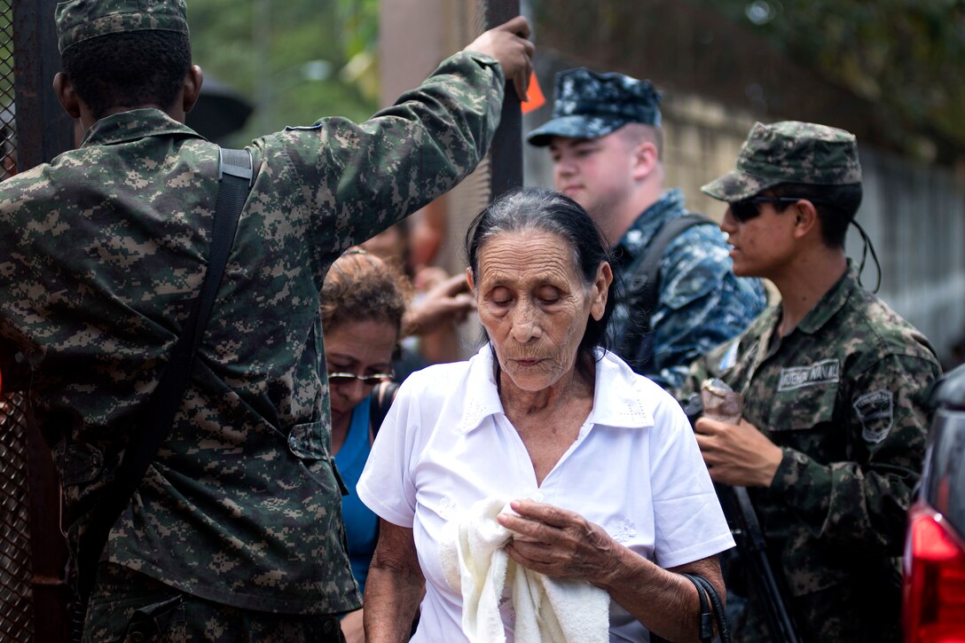 American and Honduran sailors greet Honduran women patients.