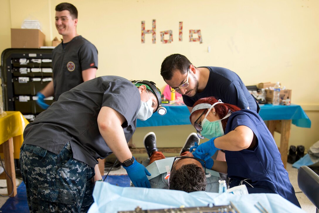 A student dentist and sailors provide dental care to a patient.