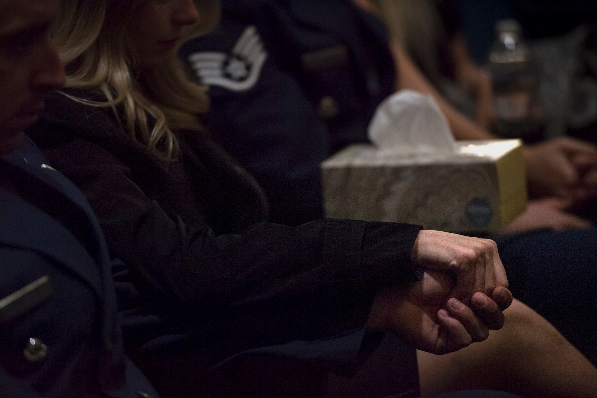 Guests hold hands during a memorial service in honor of Capt. Mark Weber, March 21, 2018, at Moody Air Force Base, Ga. Weber, a 38th Rescue Squadron combat rescue officer and Texas native, was killed in an HH-60G Pave Hawk crash in Anbar Province, Iraq, March 15. During the ceremony, Weber was posthumously awarded a Meritorious Service Medal and the Air Force Commendation Medal. (U.S. Air Force photo by Staff Sgt. Ryan Callaghan)