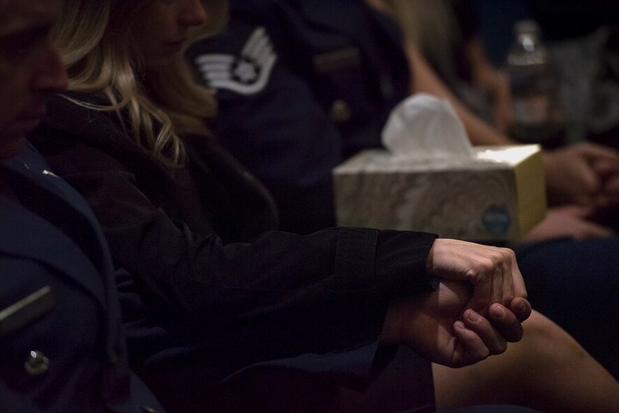 Guests hold hands during a memorial service in honor of Capt. Mark Weber, March 21, 2018, at Moody Air Force Base, Ga. Weber, a 38th Rescue Squadron combat rescue officer and Texas native, was killed in an HH-60G Pave Hawk crash in Anbar Province, Iraq, March 15. During the ceremony, Weber was posthumously awarded a Meritorious Service Medal and the Air Force Commendation Medal. (U.S. Air Force photo by Staff Sgt. Ryan Callaghan)