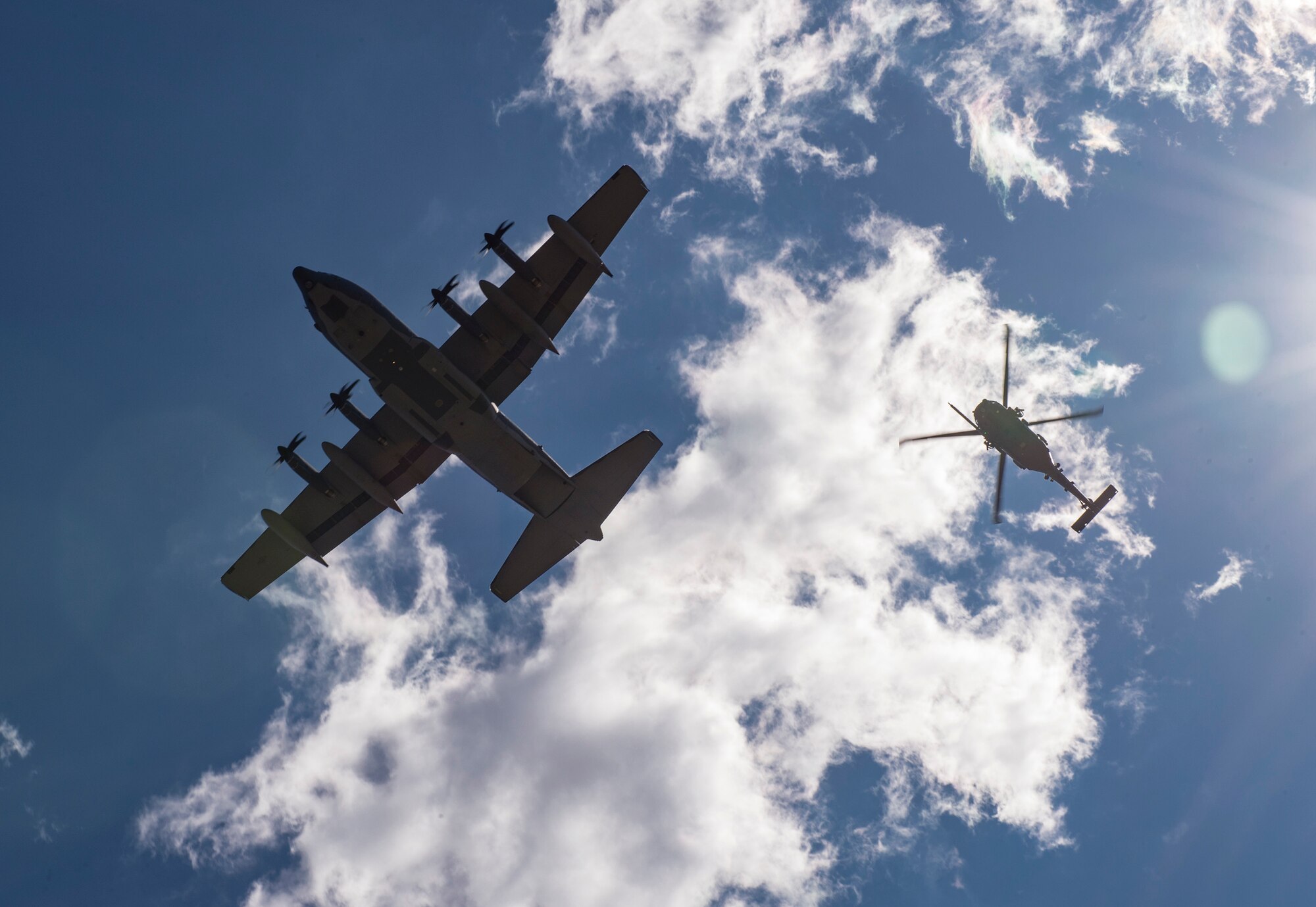 An HC-130J Combat King II and an HH-60G Pave Hawk fly over a formation of Airmen following a memorial service in honor of Capt. Mark Weber, March 21, 2018, at Moody Air Force Base, Ga. Weber, a 38th Rescue Squadron combat rescue officer and Texas native, was killed in an HH-60G Pave Hawk crash in Anbar Province, Iraq, March 15. During the ceremony, Weber was posthumously awarded a Meritorious Service Medal and the Air Force Commendation Medal. (U.S. Air Force photo by Andrea Jenkins)