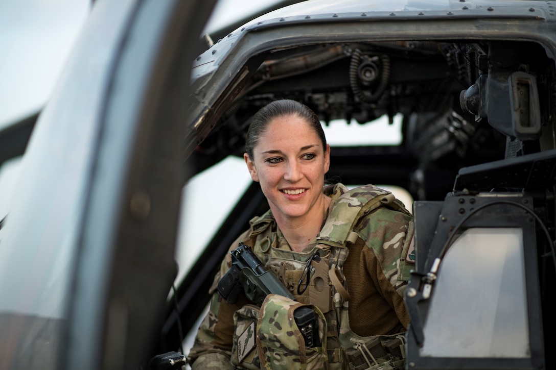 Helicopter pilot poses sitting at the door of her aircraft.