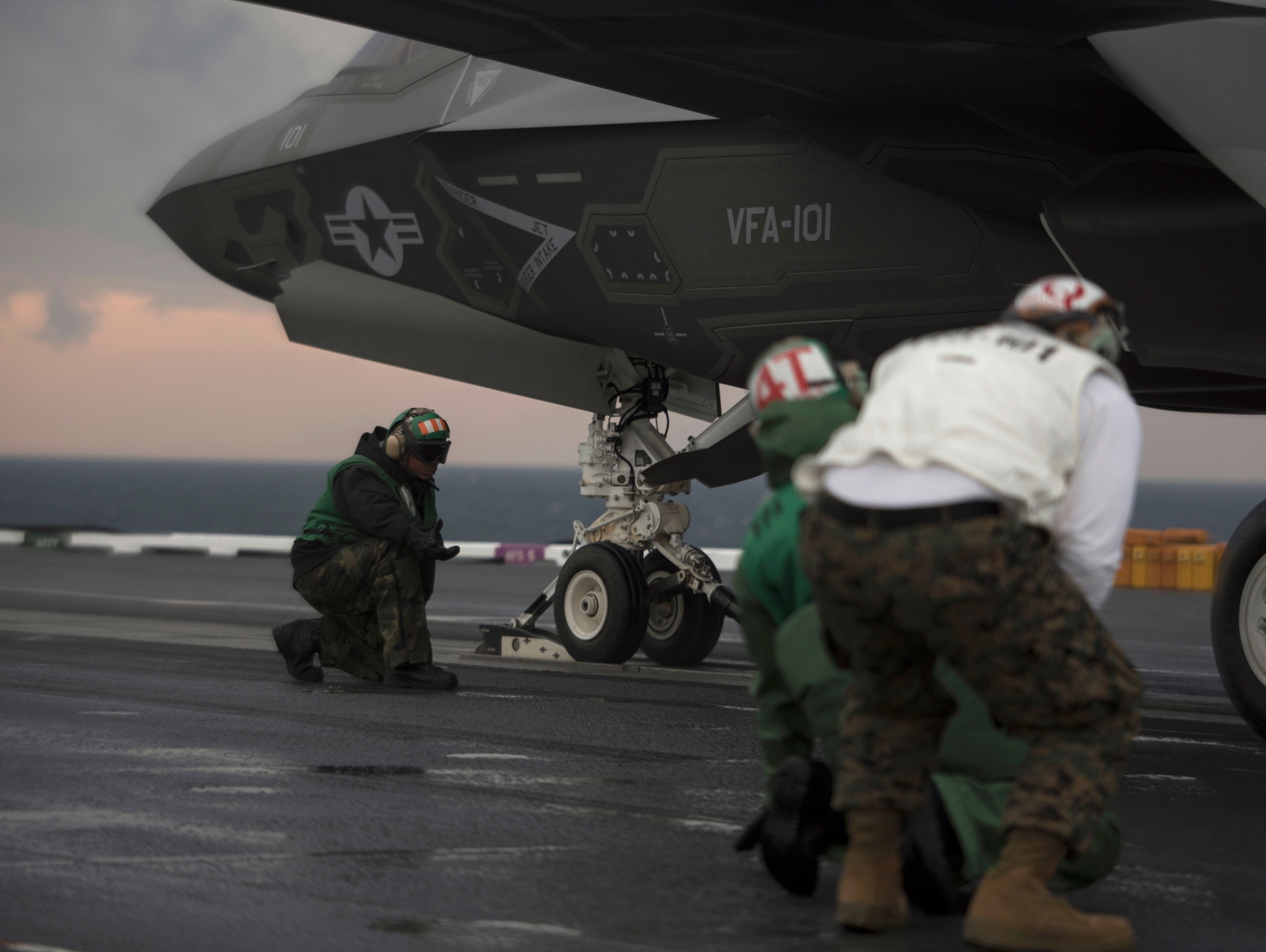 Flight deck crew members assigned to Strike Fighter Squadron (VFA) 101 and USS Abraham Lincoln (CVN-72) aviation department, stand near an F-35C Lightning II March 17, 2018, in the Altantic Ocean. (U.S. Air Force photo by Staff Sgt. Peter Thompson/Released)