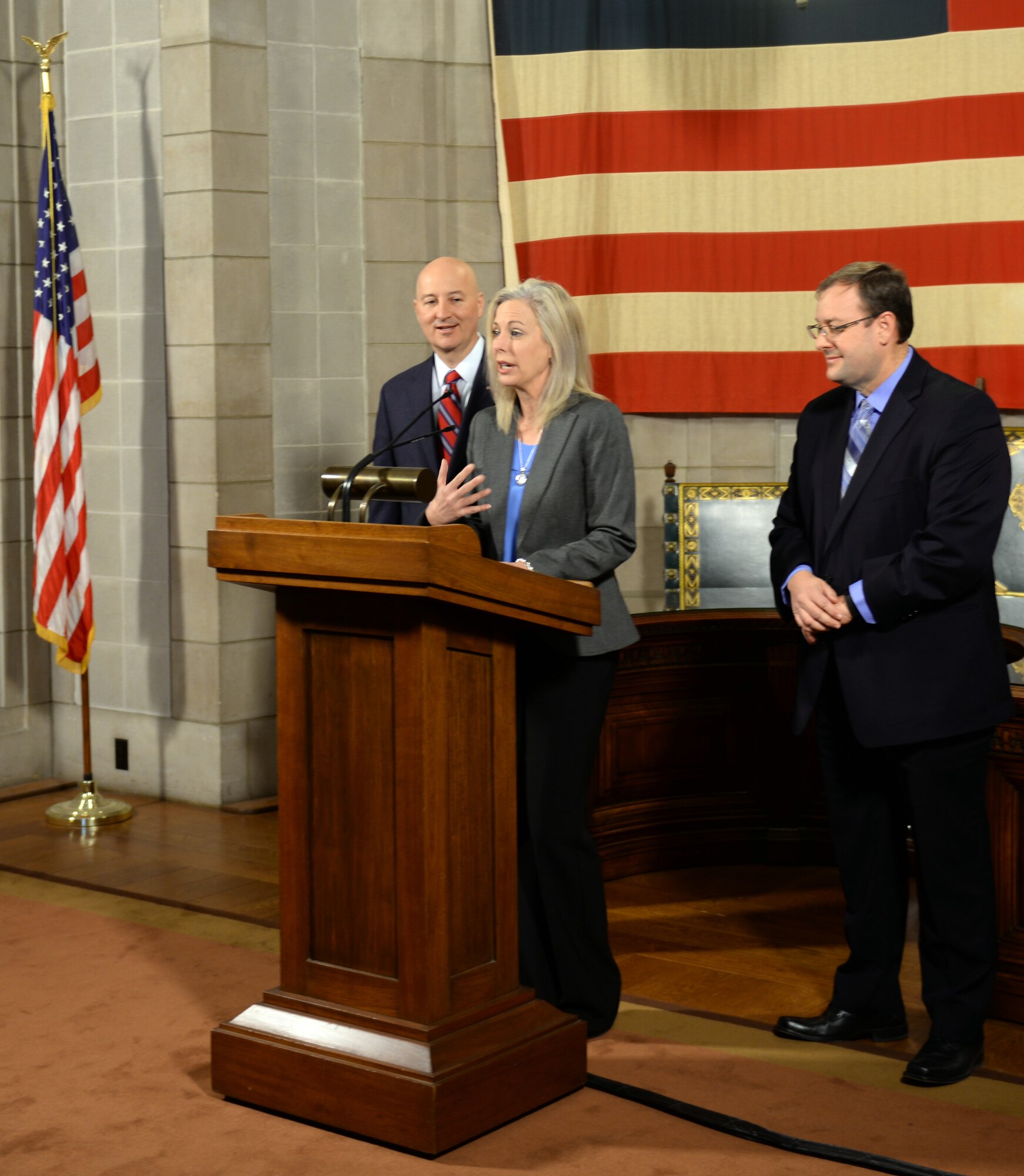 Shannon Manion, a certified teacher and veteran school administrator as well as the spouse of Col. Michael Manion, 55th Wing commander, addresses the media as Nebraska Gov. Pete Ricketts and Matt Blomstedt, commissioner of the Nebraska Department of Education, look on at the Nebraska State Capitol in Lincoln, Nebraska on March 19, 2018. According to the governor, manion was instrumental in changing Rule 21 which regulates state teaching licenses and will make it easier for military spouses to teach immediately if they have recently arrived from out of state.