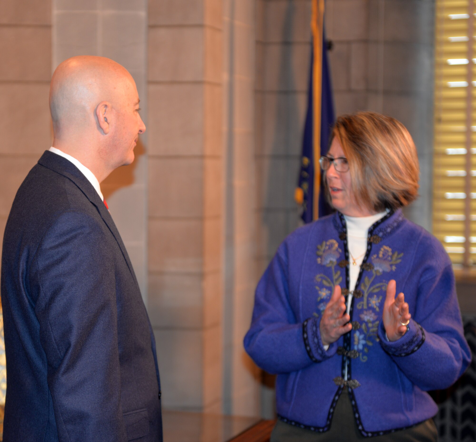 Julie Copley, spouse of Rear Adm. Curt Copley, U.S. Strategic Command (USSTRATCOM) Navy Element Commander and Director of Intelligence, discusses issues and challenges facing military spouses with Nebraska Gov. Pete Ricketts March 19, 2018, at the Nebraska State Capitol in Lincoln, Nebraska. Copley was on-hand, along with other Offutt-based military spouses, to witness the governor sign a rule change which will make it easier for military spouses to teach immediately if they have recently arrived from out of state.