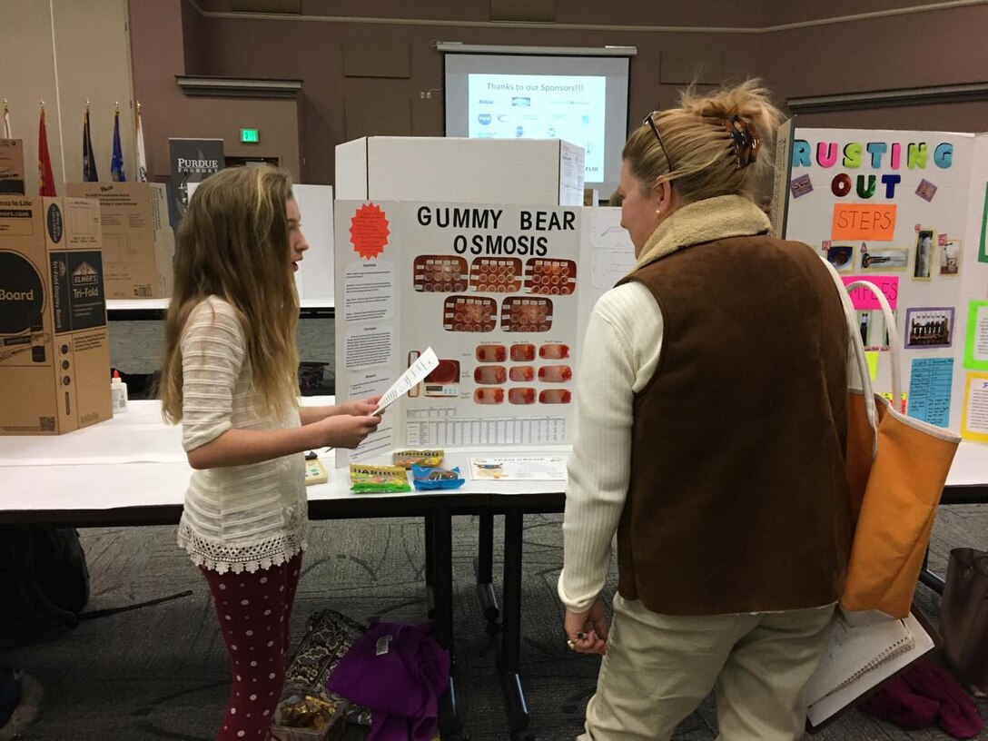 CRANE, Ind. – Adalyn Wiseman, 7th grade, Bloomfield Junior Senior High School speaks with attendee at the 34th Annual Team Crane Science Fair. Students from 11 area school systems entered a record 200 projects to compete for awards and cash prizes in the 34th Annual Team Crane Science Fair held at WestGate Academy Conferencing & Training Center on Mar. 21, 2018.