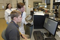 Will Buttrey (center), an undergraduate student from the University of Tennessee, Knoxville (UTK), and Brendon Arnold, with the Integrated Manufacturing and Project Management Office at Naval Surface Warfare Center, Carderock Division, look at the data acquisition system for mechanical testing in an environmental chamber March 15, 2018, while Dr. Stephanie TerMaath, an associate professor at UTK, looks on at Carderock's West Bethesda, Md., headquarters. TerMaath and Buttrey are part of the Naval Engineering Education Consortium with Carderock's researching AM material qualification and parts certification.