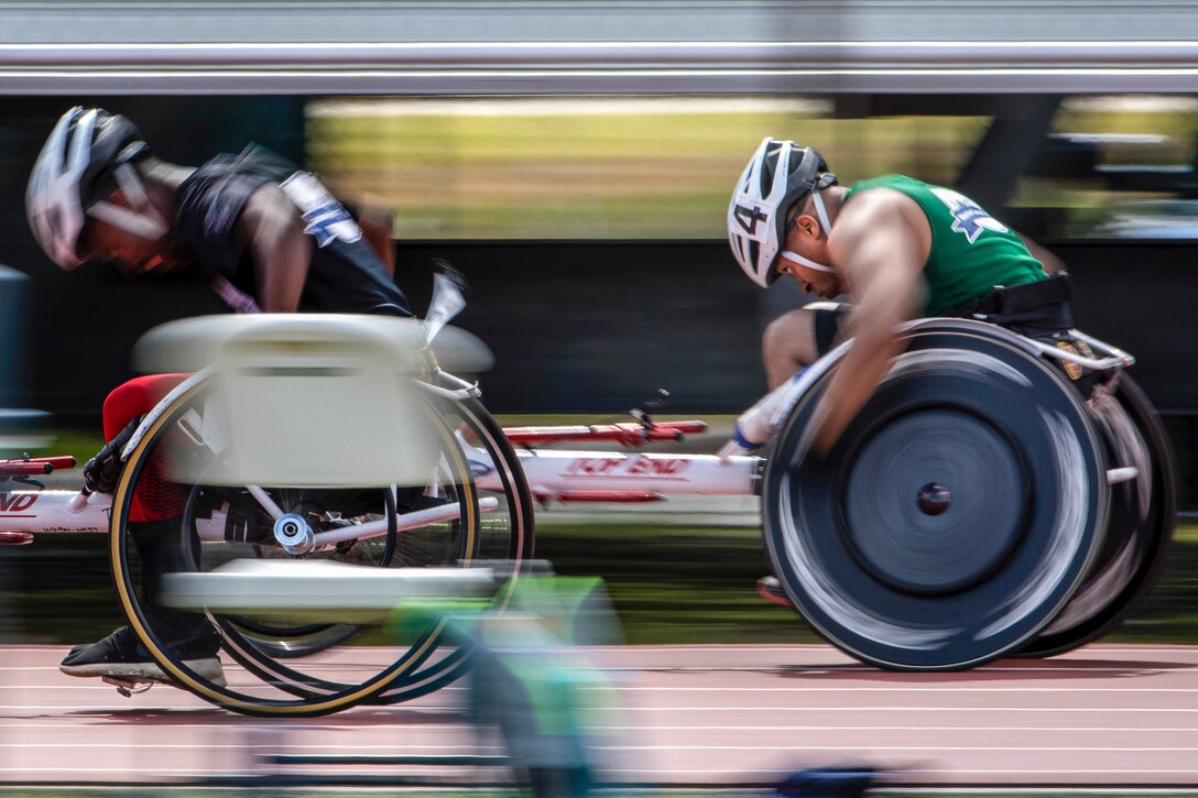 Two Marine Corps athletes race in wheelchairs on a track.