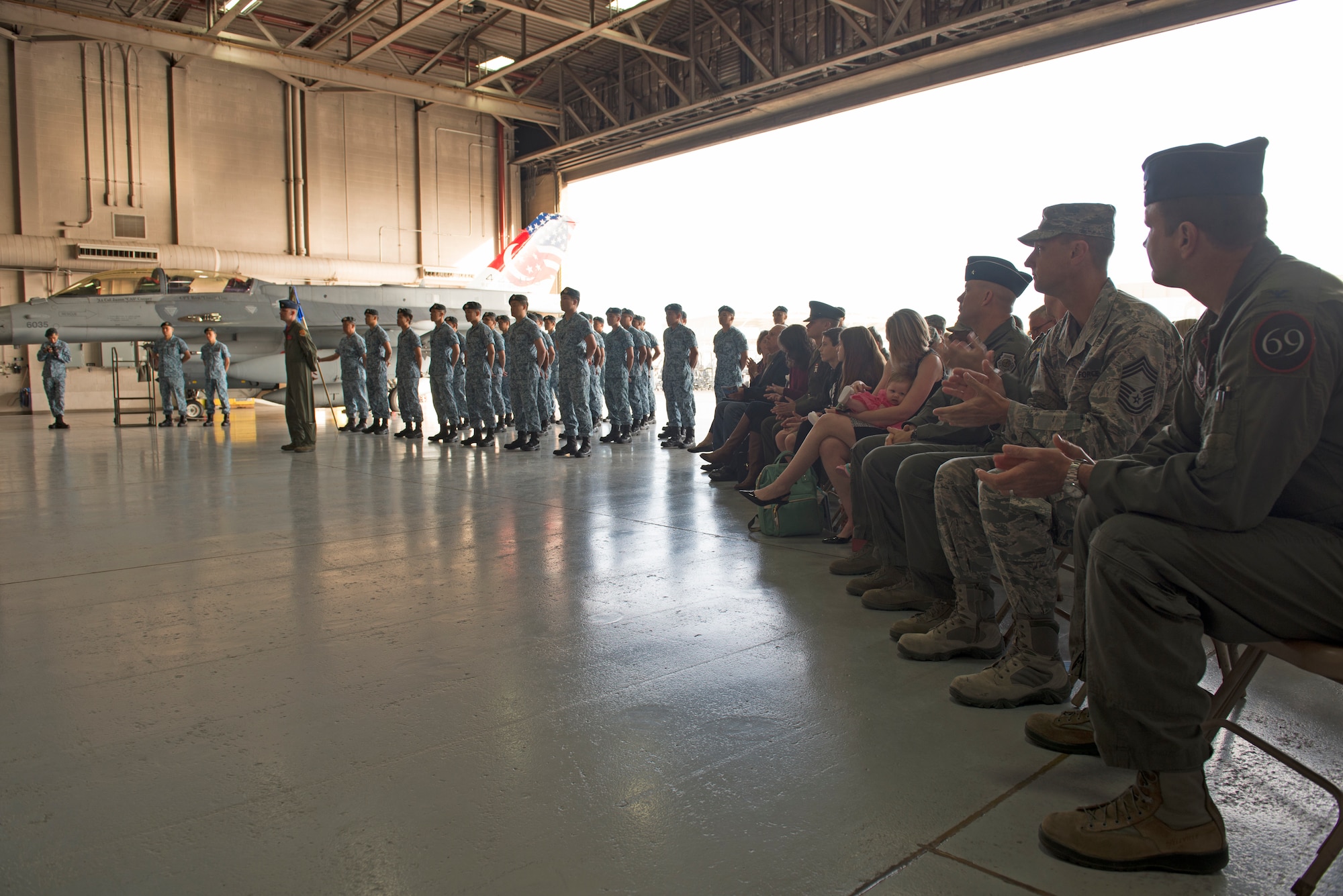 Luke's command team, friends and family of both pilots, bear witness to the 425th Fighter Squadron's change of command ceremony while members of the squadron stand in formation to honor their old and new commanders at Luke Air Force Base, Ariz. March 16, 2018. Lt. Col. Mark Whisler assumed command from Lt. Col. Jason Cooper. (U.S. Air Force photo/Senior Airman Ridge Shan)
