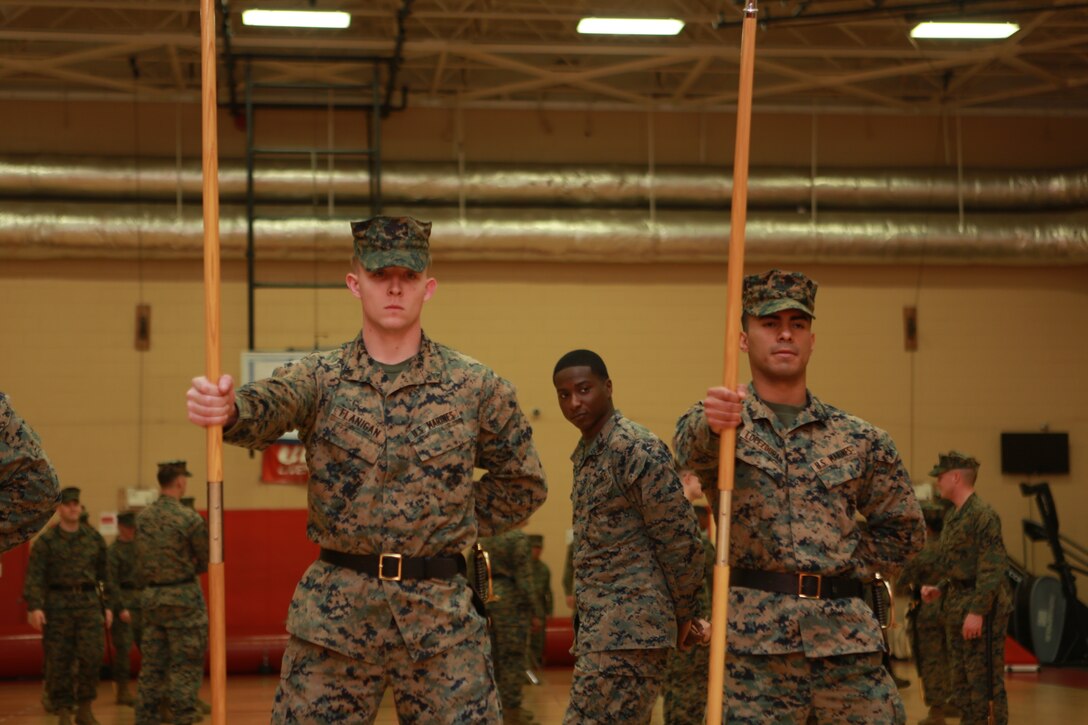 Sgt. Devin Brown, instructor, Corporal’s Course 630-18, U.S. Marine Corps Forces Command, inspects Cpl. Patrick Flanigan and Cpl. Benigno Lopez-Duran during their guidon practice at Hopkins Hall Gym aboard Camp Allen, Norfolk, Va., March 21. Brown worked to prepare his students for their drill exam by fine tuning the techniques and repetition. (Official U.S. Marine Corps photo by Sgt. Mark Tuggle/Released)