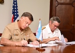Military leaders sign documents.