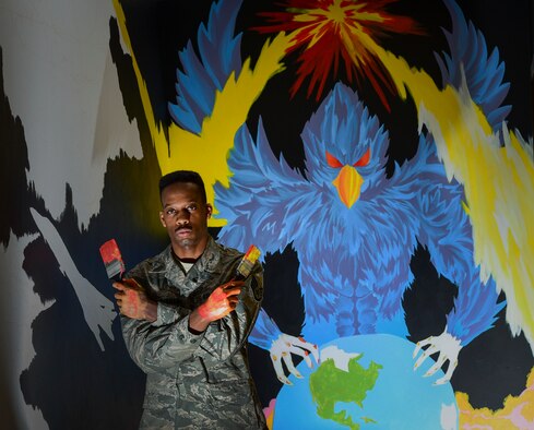 Staff Sgt. Alexander Buchanan, a 28th Operations Support Squadron aviation resource manager, stands next to an unfinished mural inside the 28th Operations Group building at Ellsworth Air Force Base, S.D., March 8, 2018. An Airman and an artist, Buchanan has spent three months designing and creating this painting outside the host aviation resource management office where he works (U.S. Air Force photo by Senior Airman Randahl J. Jenson)