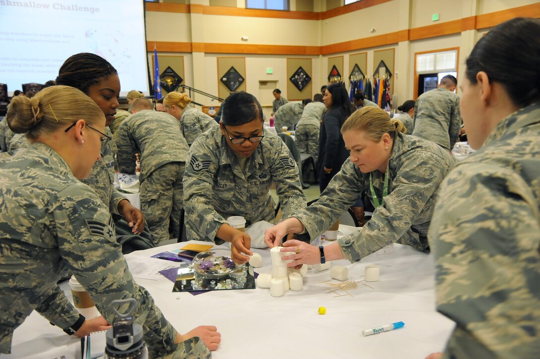 Tables of Airmen work together to create a freestanding tower using only marshmallows and toothpicks during a women’s symposium March 20, 2018, at Malmstrom Air Force Base, Mont.  Various events throughout the two-day summit challenged participants to communicate and work together. (U.S. Air Force photo by Christy Mason)