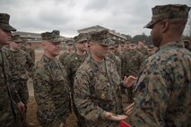 Master Chief Petty Officer Russell Folley, the command master chief of 2nd Marine Division, gives Petty Officer 2nd Class Willie Jones, a corpsman with 2nd Medical Battalion, 2nd Marine Logistics Group, a coin after a Purple Heart award ceremony at Camp Lejeune N.C., Feb. 8, 2018. Jones was awarded the Purple Heart for injuries sustained from a vehicle borne improvised explosive device in Afghanistan, Sept. 6 2017. Despite his own injuries, Jones provided aid for injured service members when a VBIED detonated during a patrol. (U.S. Marine Corps photo by Cpl. Victoria Ross)