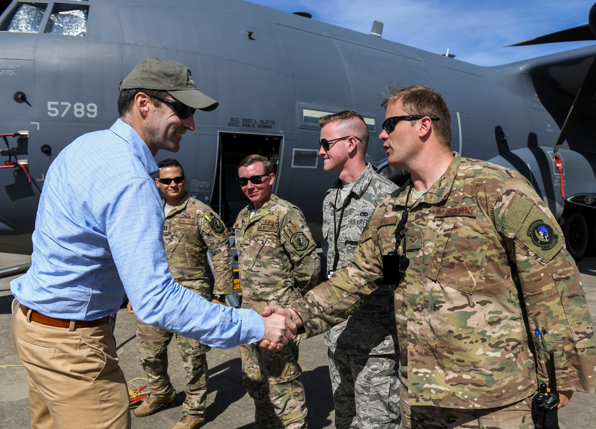 People greeting one another and exchanging handshakes on a flight line.