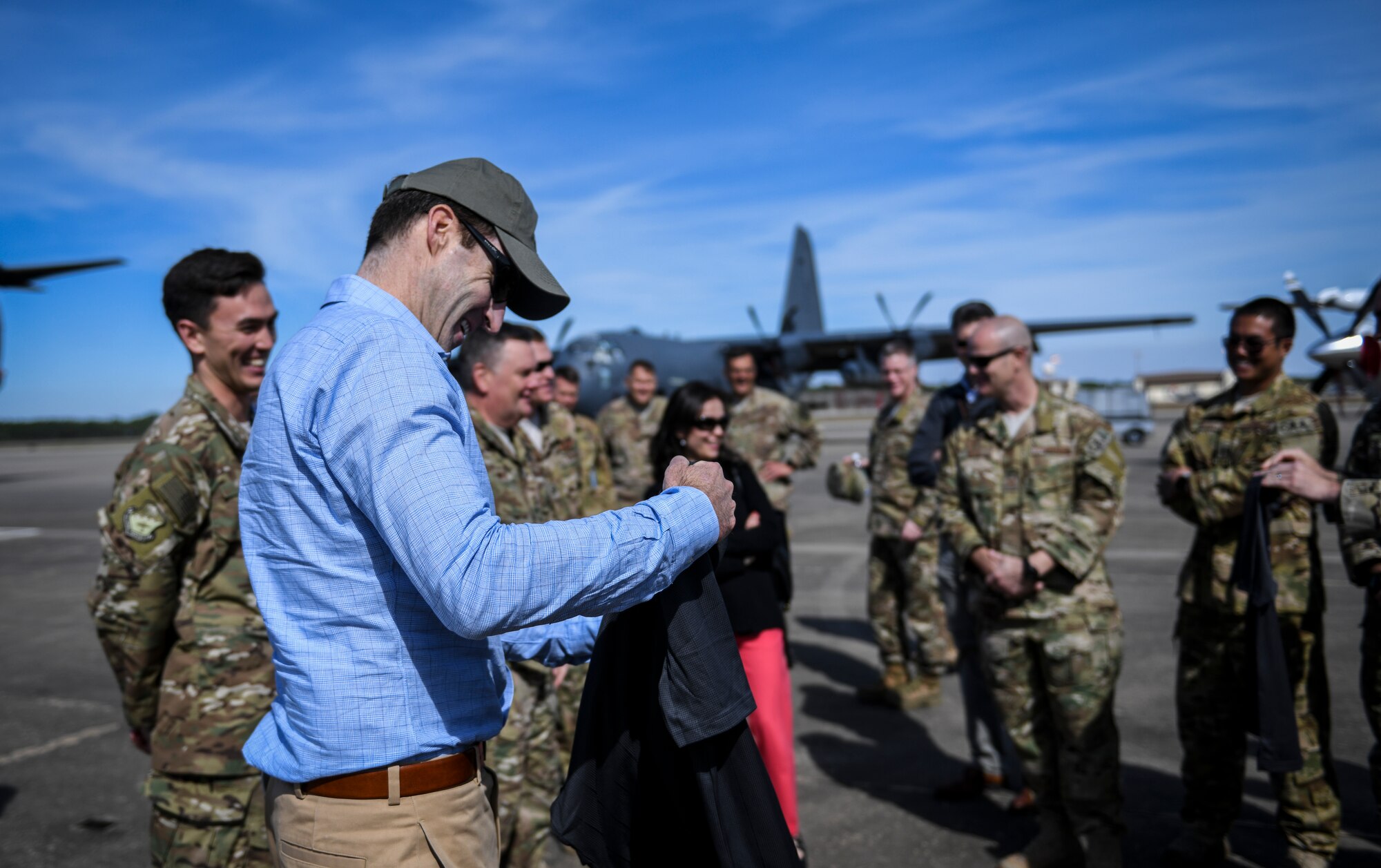Man receiving shirt from group of people on a flight line.
