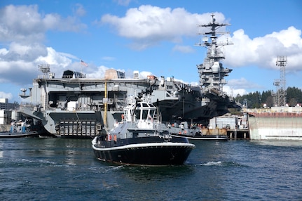 Harbor tug Defiant (YT 804) and crew wait to assist while USS Nimitz (CVN 68) is being positioned for docking at Puget Sound Naval Shipyard & Intermediate Maintenance Facility in Bremerton, Washington March 1, 2018.