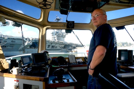 Jan Carlson, captain of Manhattan (YT 800), listens as a crew member provides a status update during the docking of USS Nimitz (CVN 68) at Puget Sound Naval Shipyard & Intermediate Maintenance Facility in Bremerton, Washington March 1, 2018.