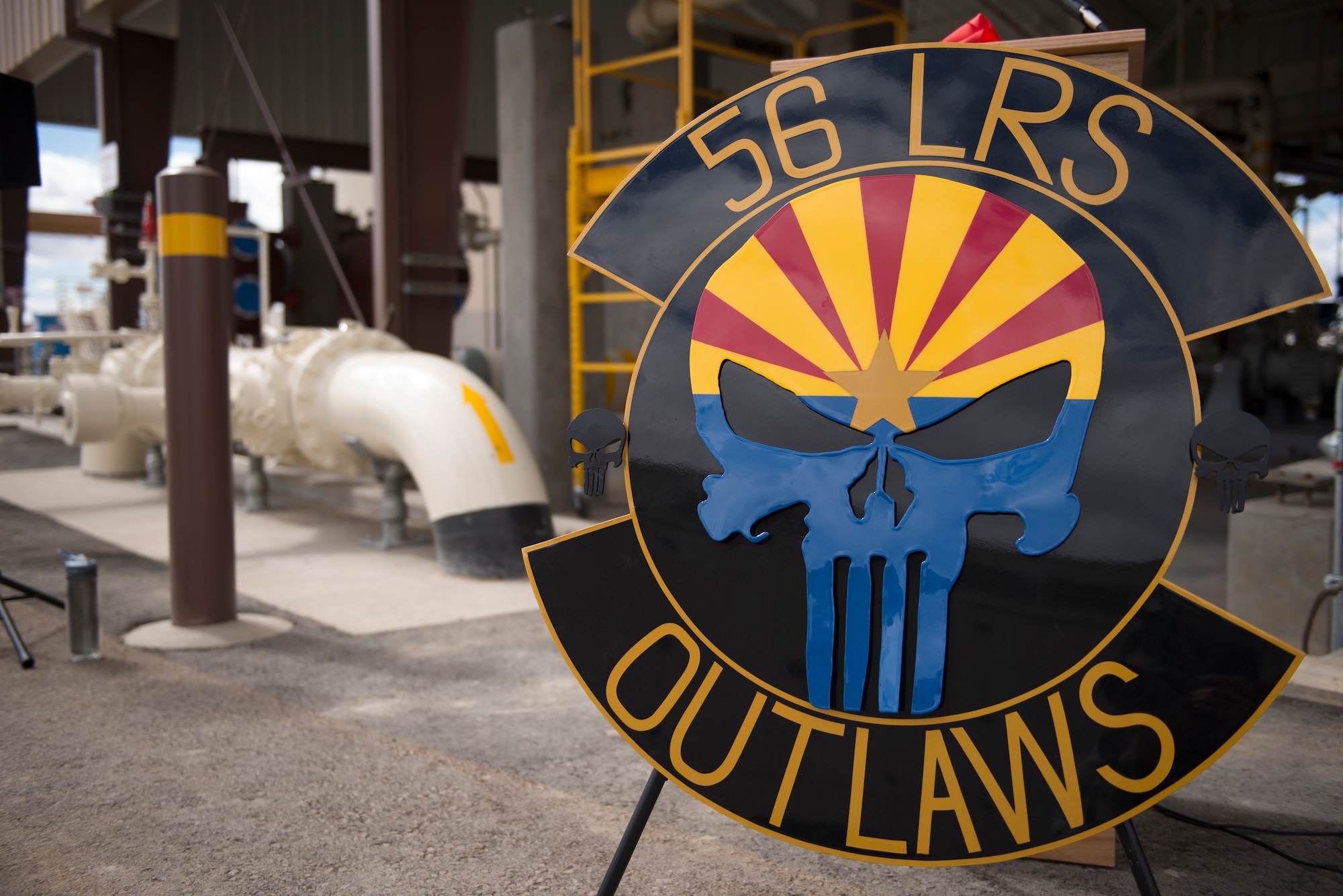 The 56th Logistics Readiness Squadron emblem sits in front of the new fuel pump house during its ribbon cutting ceremony at Luke Air Force Base, Ariz., March 15, 2018. The pump house and an adjacent fill house on the flight line is expected to save fuel management operators significant time and speed up the jet refuel and sortie rate. (U.S. Air Force photo by Senior Airman Ridge Shan)
