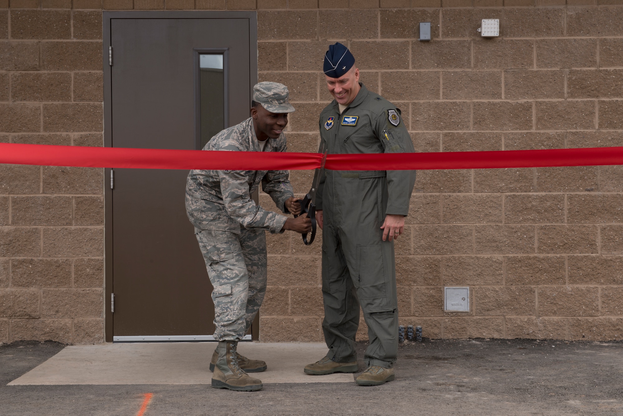 Airman Johnny Jackson, 56th Logistics Readiness Squadron Fuels Management operator, cuts the ribbon with Brig. Gen. Brook Leonard, 56th Fighter Wing commander, to open the new fuel pump house at Luke Air Force Base, Ariz., March 15, 2018. Leonard and other members of Luke’s command team were present for the pump house’s ribbon-cutting ceremony. (U.S. Air Force photo by Senior Airman Ridge Shan)