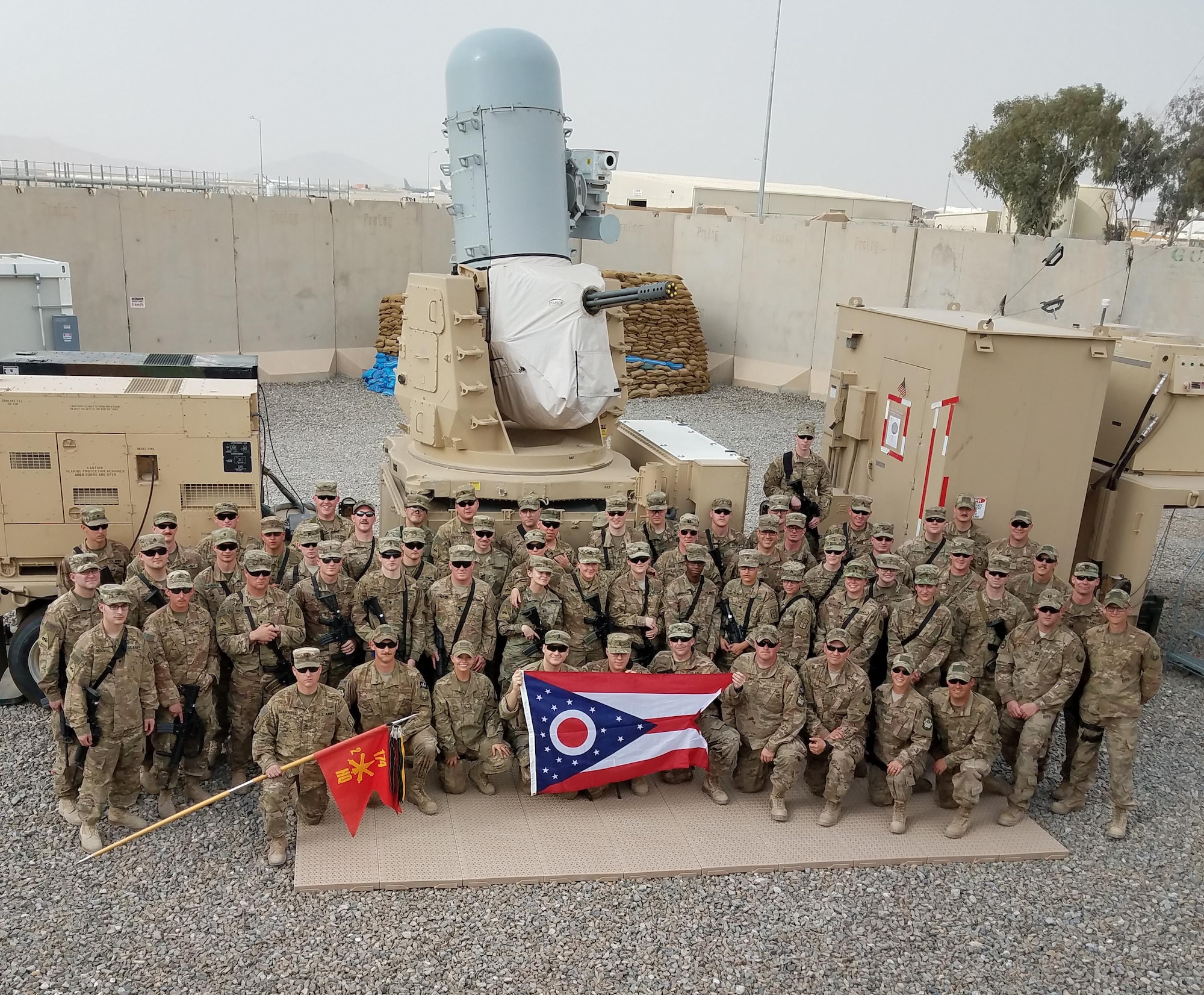 Airmen with the 220th Engineering Installation Squadron, Ohio Air National Guard, and Soldiers with the 2nd Battalion, 174th Air Defense Artillery Regiment, Ohio Army National Guard, pose for a group photo in front of one of the Army's Counter-Rocket, Artillery, and Mortar (C-RAM) Intercept weapon systems at Kandahar Airfield, Afghanistan, March 10, 2018.