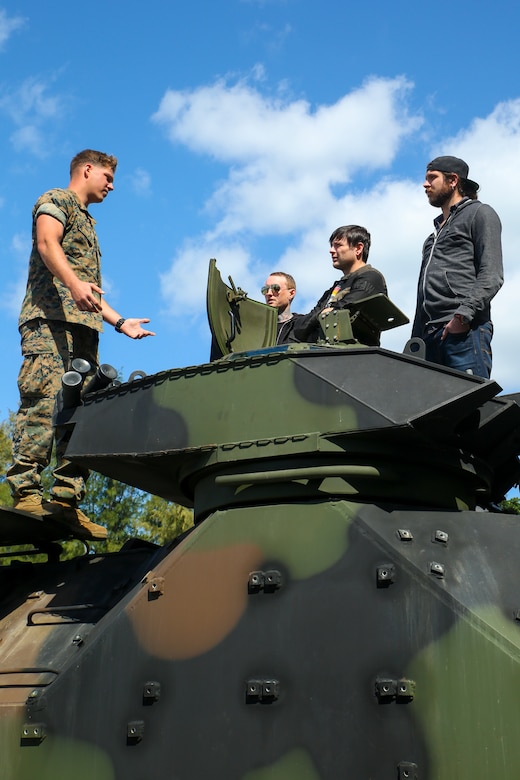 Sgt. Dustin Conklin, left, explains the different parts of the assault amphibious vehicle during a meet and greet with rock band, Asking Alexandria, March 23 aboard Camp Schwab, Okinawa, Japan. Band members were able to get close and learn about the different military vehicles while meeting with Marines. The band later performed for Marines and their families at the Annual Schwab Festival. Conklin is an AAV crew chief with AAV Company B, 4th AAV Battalion. (U.S. Marine photo by Pfc. Nicole Rogge)