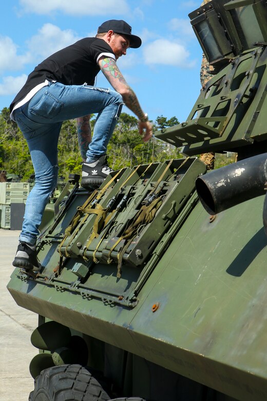Sam Bettley climbs up the side of an light armored vehicle during a meet and greet with Marines March 23 aboard Camp Schwab, Okinawa, Japan. Band members were able to get close and learn about the different military vehicles while meeting with Marines. The band later performed for Marines and their families at the Annual Schwab Festival. Bettley is the bassist for rock band, Asking Alexandria. (U.S. Marine photo by Pfc. Nicole Rogge)