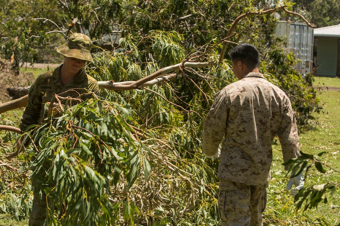 U.S. Marine Corps 1st Lt. Johnathan Wong, communications officer with Marine Rotational Force (MRF) Darwin (advanced party), and an Australian Defence Force service member, clear nearby roadways of tree branches at Larrakeyah Defence Precinct, Darwin, NT, Australia March 18, 2018. Marines and Australian Defence Force service members aided in cleaning up debris found throughout the installation after Tropical Cyclone Marcus swept across parts of the northern coast of Australia. The Marines are part of an advanced echelon preparing for MRF-D. (U.S. Marine Corps photos by Lance Cpl. Mason Roy)