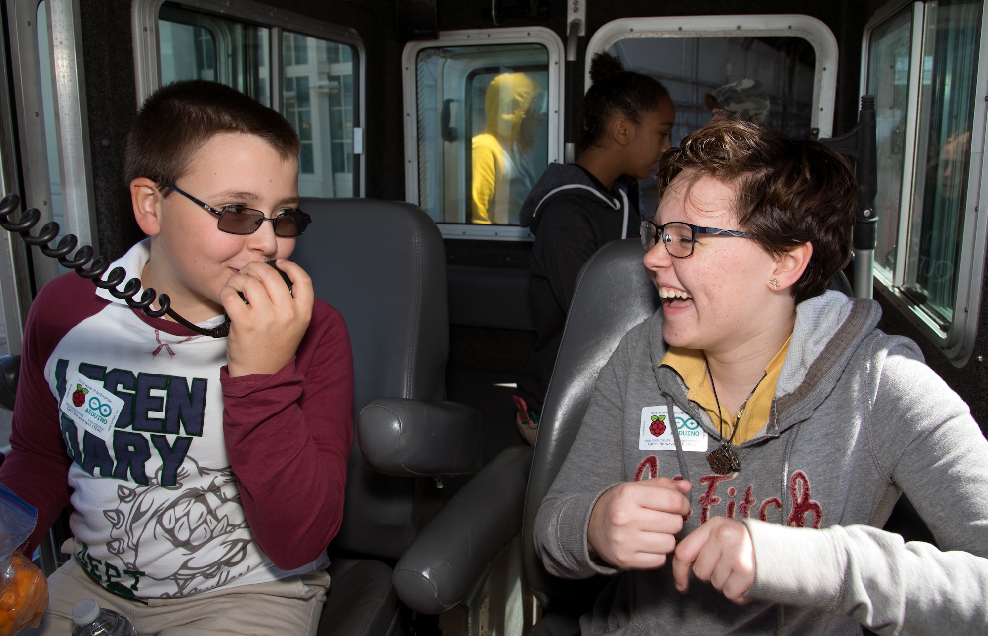 Two young students share a laugh while talking about the public address system upon a secured all-around flotation equipped (SAFE) boat during the Science, Technology, Engineering, Arts and Math (STEAM) Day at MacDill Air Force Base, Fla., March 21, 2018.