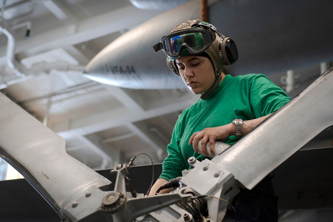 A sailor checks for corrosion on a helicopter’s tail rotor.