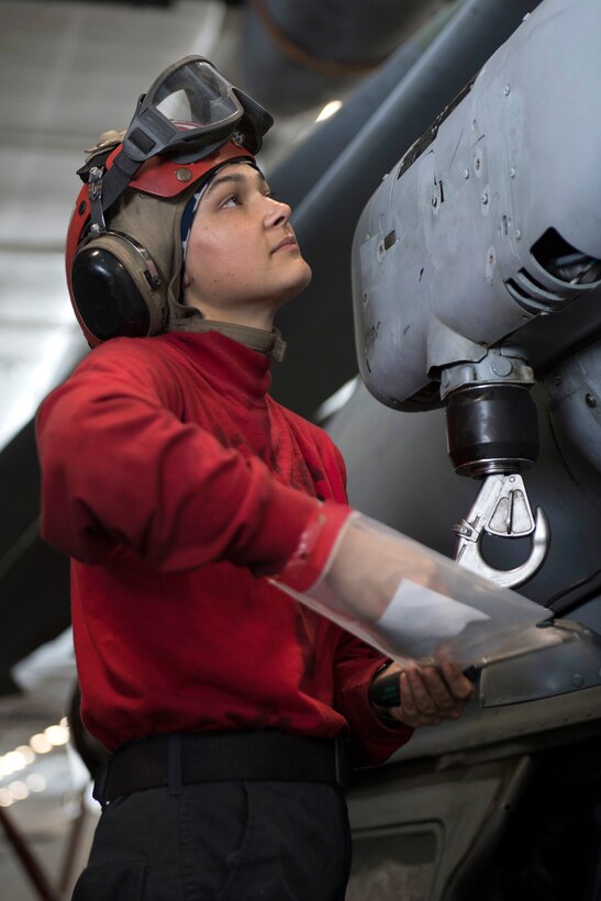 A sailor installs parts on an MH-60S Sea Hawk helicopter.