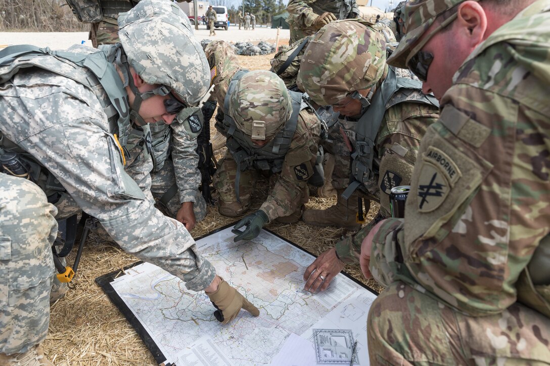 Soldiers point at a map during land navigation training.
