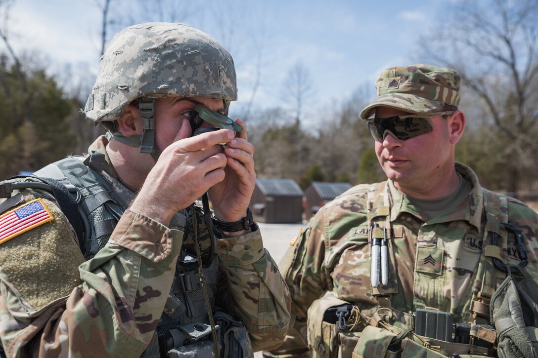 A soldier is graded by another soldier while using a compass.