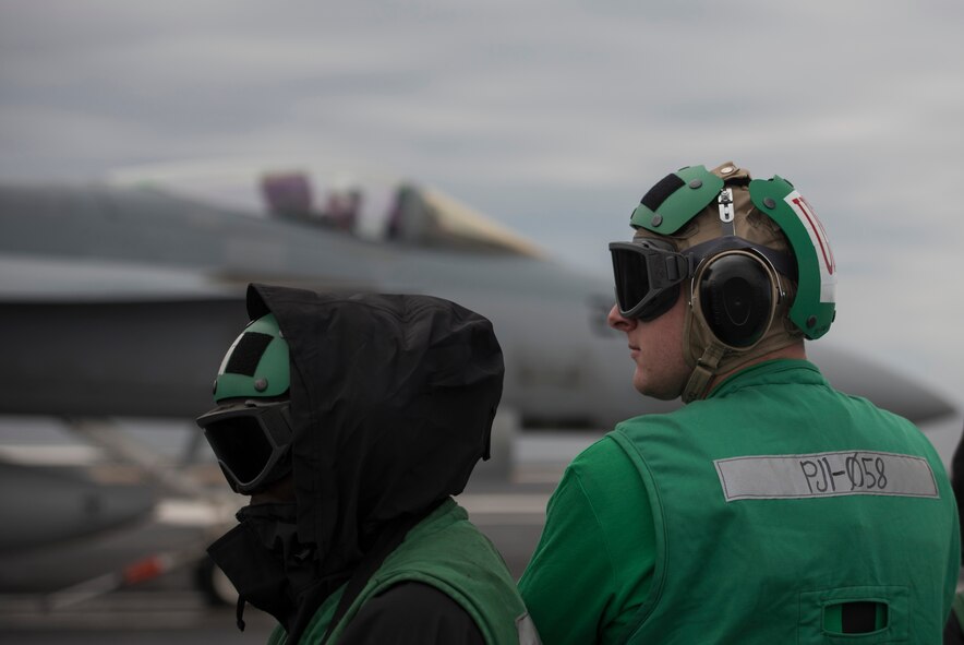 U.S. Air Force 1st Lieutenant Sean Duval, 33rd Maintenance Squadron maintenance operations officer, right, stands near the bow catapults during flight deck operations March 19, 2018, on the Nimitz-class aircraft carrier USS Abraham Lincoln (CVN-72). Duval participated in a maintenance officer exchange with a member of Strike Fighter Squadron (VFA) 101. The exchange gave Duval useful insight into Navy maintenance operations and helped him connect to his families history in the U.S. Navy. (U.S. Air Force photo by Staff Sgt. Peter Thompson/Released)