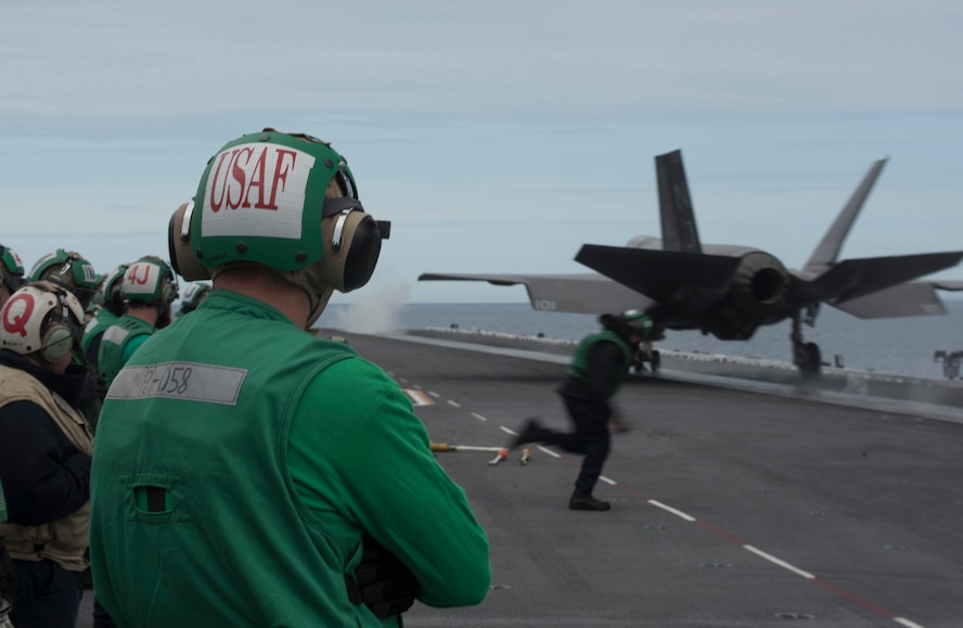U.S. Air Force 1st Lieutenant Sean Duval, 33rd Maintenance Squadron maintenance operations officer, stands near the bow catapults as an F-35C Lightning II assigned to Strike Fighter Squadron (VFA) 101 is launched March 19, 2018, on the Nimitz-class aircraft carrier USS Abraham Lincoln (CVN-72). Duval plans to use what he learned during his maintenance officer exchange to help improve his unit back at Eglin Air Force Base, Fla. (U.S. Air Force photo by Staff Sgt. Peter Thompson/Released)