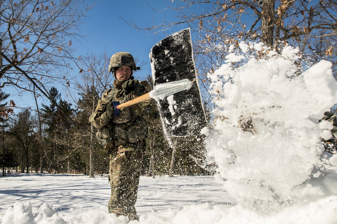 A soldier shovels snow.