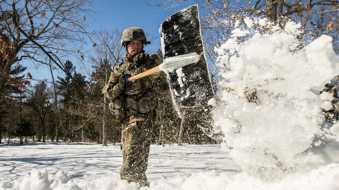 A soldier shovels snow.