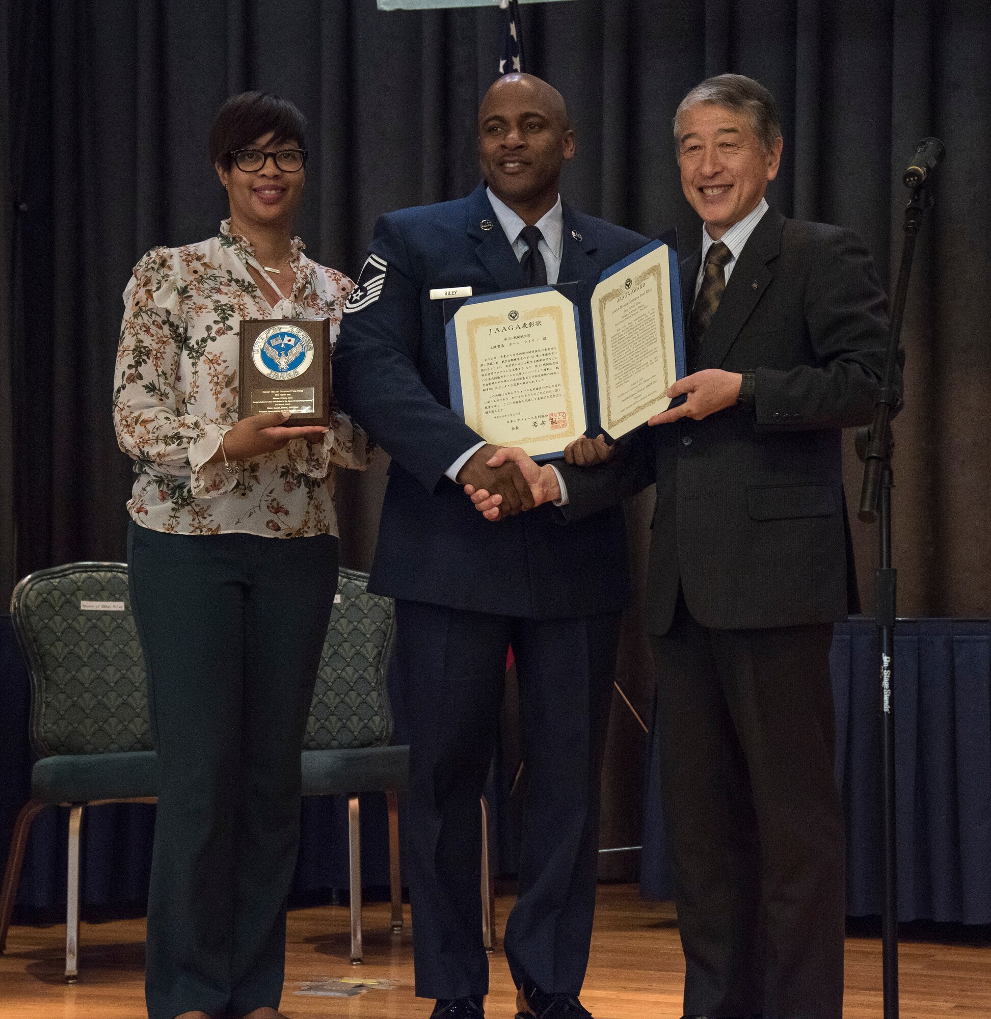 Shereda Riley, left, wife of Senior Master Sgt. Paul Riley, center, the 35th Maintenance Squadron armament flight chief, and Retired General Yoshiyuki Watanabe, right, the Japan-American Air Force Goodwill Association vice president, pose for a photo at Misawa Air Base, Japan, March 20, 2018. Riley earned the recognition for his efforts in leading the 35th Fighter Wing’s bilateral relations team. (U.S. Air Force photo by Airman 1st Class Collette Brooks)