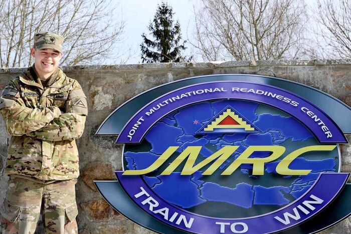 A man stands next to an illustrated sign.