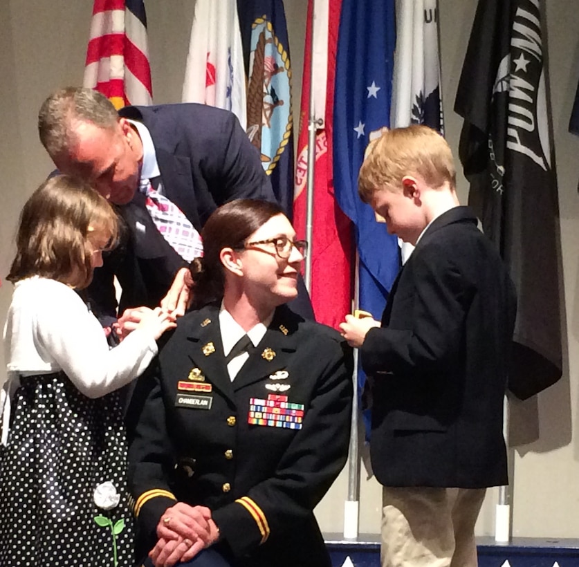 The children and husband of an U.S. Army officer help apply her new rank.
