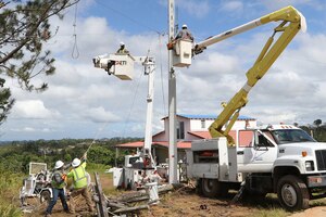 Workers reconnect power lines in Puerto Rico.