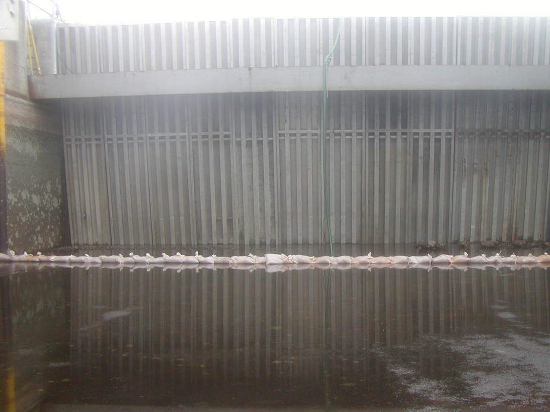 A view from the inside of the dewatered Ortona Lock chamber. The needle beam system is fully installed, holding back about 11 feet of water on the other side. Sandbags help keep the area drier for workers