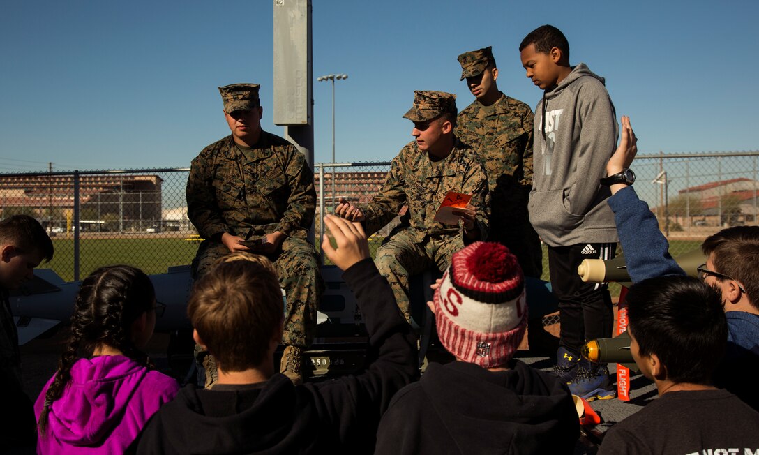 U.S. Marines assigned to Marine Aviation Logistics Squadron (MALS) 13 teach students from Castle Dome Middle School about their military occupational specialty Aviation Ordnance Systems Technicians during a tour on Marine Corps Air Station Yuma, Ariz., in partnership with the school's Character Does Matter Program March 2, 2018. Castle Dome Middle School was adopted by MALS-13 through the Adopt-a-School Program. The Character Does Matter Program’s goal is to empower veterans and families of fallen heroes to develop character in future generations. (U.S. Marine Corps photo taken by Cpl. Christian Cachola)