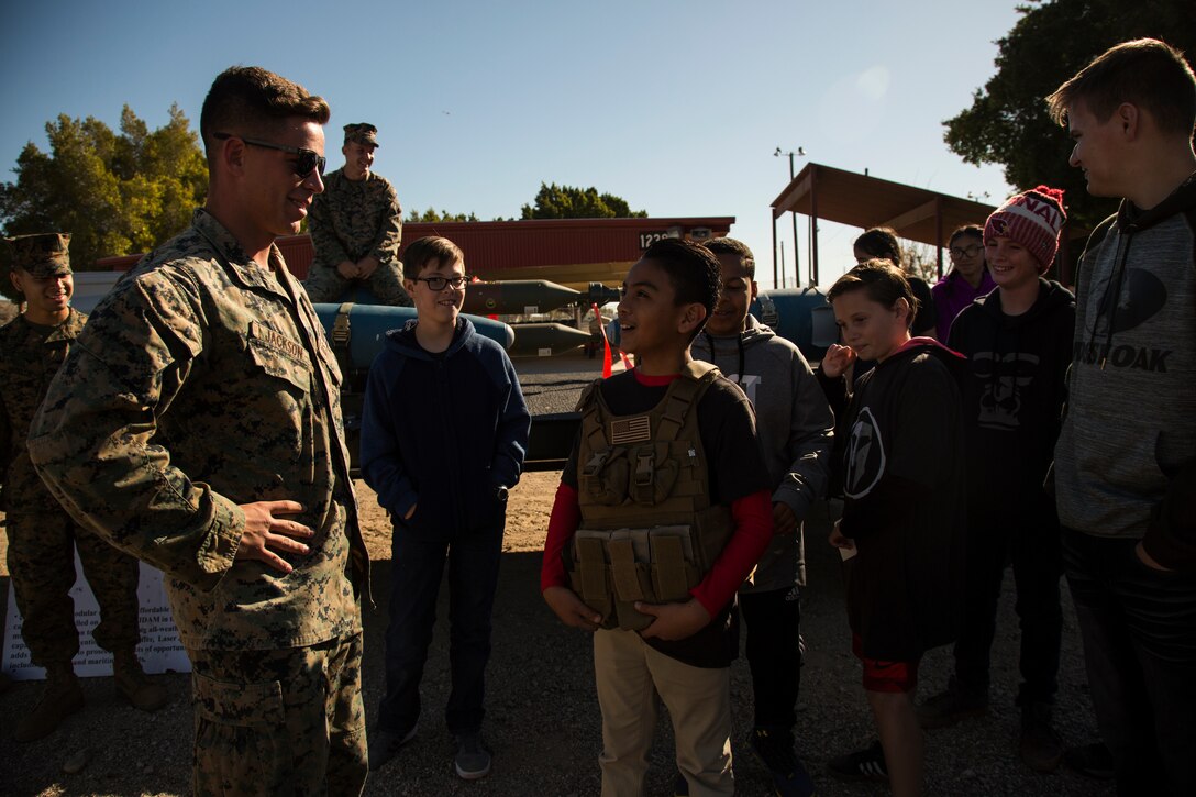 U.S. Marine Corps Lance Cpl. Cody Jackson, an aviation ordnance systems technician assigned to Marine Aviation Logistics Squadron (MALS) 13, lends a student from Castle Dome Middle School his plate carrier system during a tour on Marine Corps Air Station Yuma, Ariz., in partnership with the school's Character Does Matter Program March 2, 2018. Castle Dome Middle School was adopted by MALS-13 through the Adopt-a-School Program. The Character Does Matter Program’s goal is to empower veterans and families of fallen heroes to develop character in future generations. (U.S. Marine Corps photo taken by Cpl. Christian Cachola)