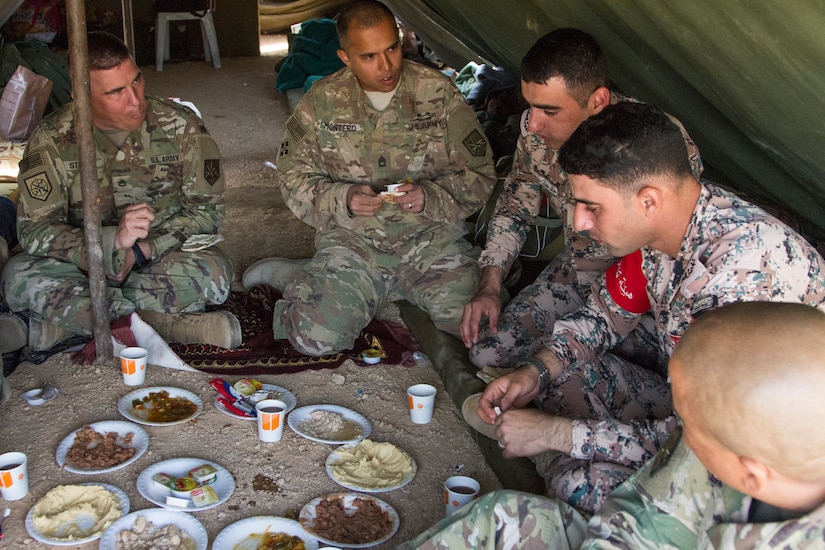 Soldiers from the Jordan Armed Forces Noncommissioned Officer Academy share a meal with U.S. Soldiers from the 648th Military Engagement Team, Georgia Army National Guard, during the culminating exercise of the JAF NCOA Squad Leader Course, March 19, 2018, near Amman, Jordan. The 648th MET advised JAF NCOA instructors as the Jordanian leaders developed the program of instruction for the course, which is attended by their soldiers and their regional allies.