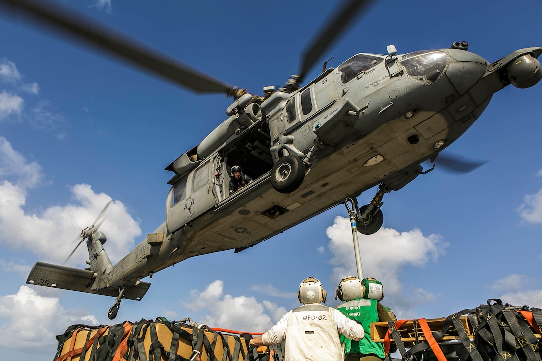 Marines and Sailors assigned to the Harpers Ferry-class dock landing ship USS Oak Hill (LSD 51) prepare to hook items for transport onto an MH-60S Seahawk helicopter attached to Helicopter Sea Combat Squadron (HSC) 28, during a replenishment-at-sea in the Aegean Sea March 24, 2018. Oak Hill, home-ported in Virginia Beach, Virginia, and the 26th MEU are conducting naval operations in the U.S. 6th Fleet area of operations. (U.S. Marine Corps photo by Staff Sgt. Dengrier M. Baez/Released)